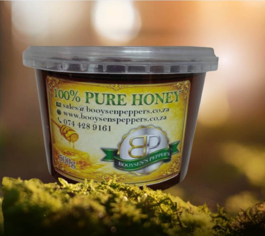 A 500g tub of Booysen's Pepper's 100% Pure Honey resting on green moss against a warm, blurred natural background. R65